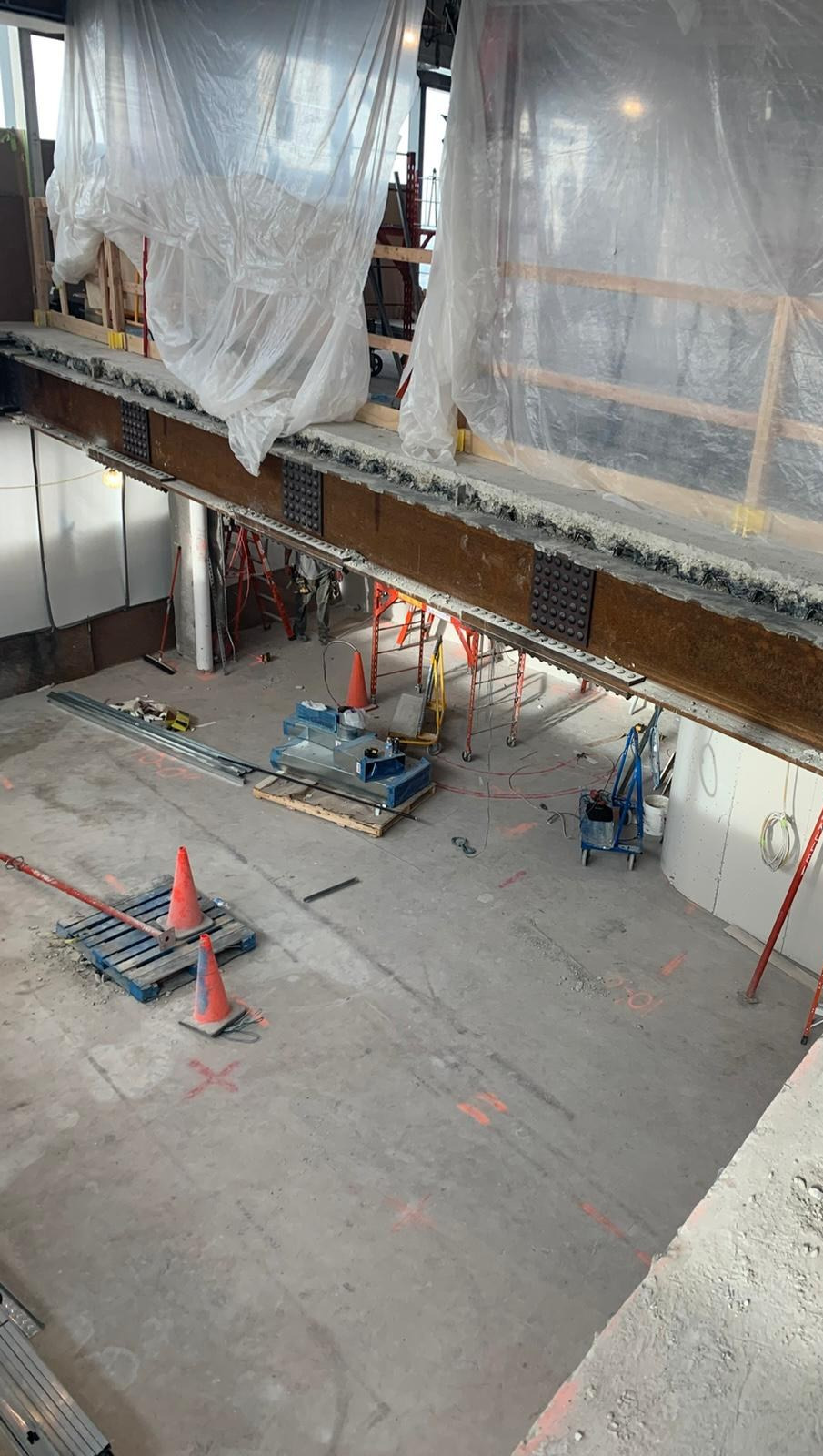 Temporary shoring beneath a new steel beam, with containment sheeting, on an Integral floor